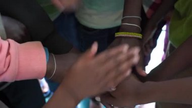 Birlik ve takım çalışması için kollar bir araya toplandı. Çemberin ortasında bir sürü el bir araya geliyor. Açık hava çekimini kapat. Birçok Afrikalı çocuk ellerini birleştiriyor, Tanzanya, Doğu Afrika