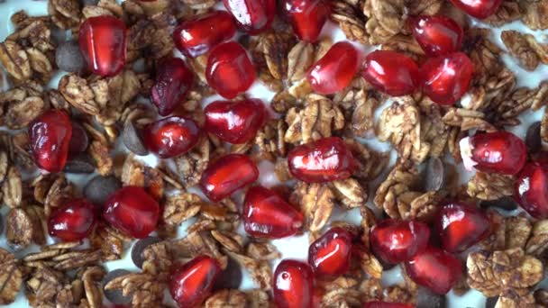 燕麦片 葡萄干 巧克力片 坚果和红色石榴籽与酸奶在一个黑色碗里 健康早餐概念 — 图库视频影像