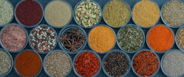 Arka planda yemek pişirmek için aromatik baharatlar, tohumlar ve kuru otlar küçük cam kaselerde, yakın plan, üst görüş