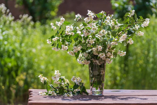 庭の木製のテーブルの上にジャスミンの枝を持つ美しい花束を閉じます ロイヤリティフリーのストック写真