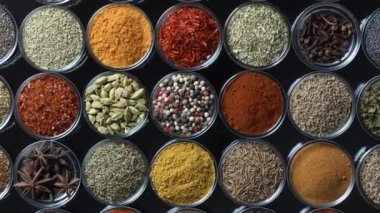 Arka planda yemek pişirmek için çeşitli aromatik baharatlar, tohumlar ve kuru otlar. Smal cam kaselerde dönüyorlar, kapatıyorlar, üstten bakıyorlar.