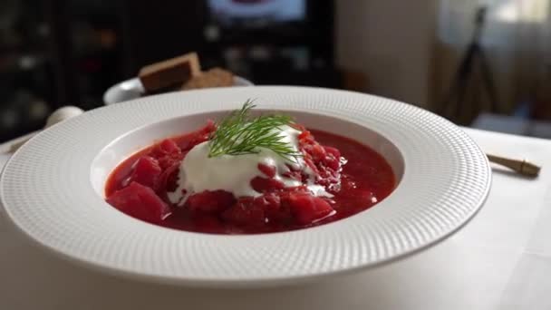 传统的乌克兰红汤或罗宋汤配红甜菜 胡萝卜 卷心菜 豆子在白碗上 一盘红甜菜汤罗宋汤轮流放在桌上 传统乌克兰食品 — 图库视频影像