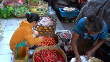 UBUD, BALI, INDONEZYA - 27 Nisan 2019: Endonezyalı fakir insanlar, Endonezya 'nın Bali adasındaki Ubud köyündeki sabah pazarında sağlıklı yiyecek satıyor ve satın alıyorlar. Sabah meyve ve sebze pazarı