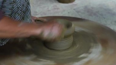 Bir kadın çömlekçinin yakın plan çekimi ayağıyla bir tekerleği döndürür ve eski şehir Hoi An, Vietnam 'da çömlek imalatında elleriyle güzel bir çömlek yapar.