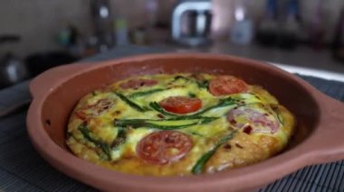 Sebzeli frittata ile seramik kase, basit vejetaryen yemeği. Yumurtalı frittata, domates, biber, soğan, peynir ve yeşil sarımsak yaprakları masada, döndür, kapat. Sağlıklı yumurta omleti.