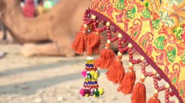 Decorative ornaments of colored threads and beads hanging on umbrella on time Pushkar Camel Mela near holy city Pushkar, Rajasthan, India, close up