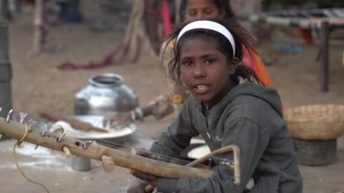 PUSHKAR, INDIA - 14 Kasım 2018: Hintli genç kız, kutsal şehir Pushkar, Rajasthan, Hindistan yakınlarındaki Pushkar Camel Mela çölünde zamanında sitarda oynuyor.