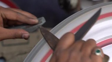 Udaipur, Rajasthan, Hindistan 'da bir pazarda makas keskinleştiren Hintli bir işçiye yakın çekim