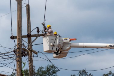 Koh Phangan, Tayland - Jan, 26, 2022: Gezici vinç kovasında duran iki erkek elektrikçi Tayland 'ın Koh Phangan adasındaki elektrik hattının kablosunu tamir ediyor