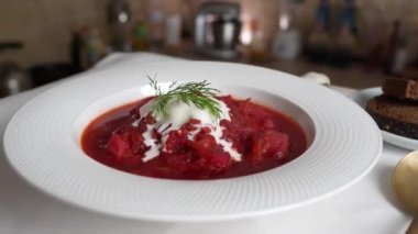 Geleneksel Ukrayna kırmızı çorbası veya kırmızı pancar, patates, havuç, lahana, beyaz kasede fasulye, yakın çekim. Bir tabak kırmızı pancar çorbası çorbası masada döner. Geleneksel Ukrayna yemekleri