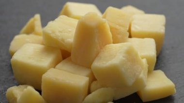 Kesilmiş peynir siyah tabakta döner. Lezzetli peynir küpleri, yaklaşın. Süt ürünleri konsepti