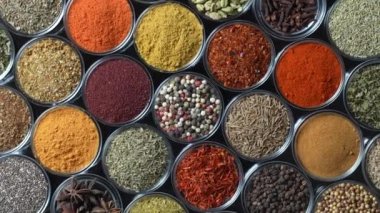 Arka planda yemek pişirmek için çeşitli aromatik baharatlar, tohumlar ve kuru otlar. Smal cam kaselerde dönüyorlar, kapatıyorlar, üstten bakıyorlar.