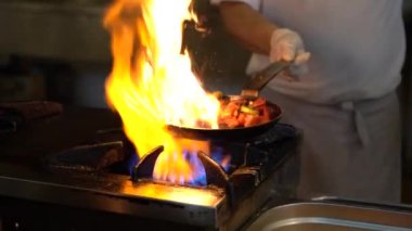 Şef, sebzeleri kızartıp tavaya atıyor. Türkiye 'deki sokak kafesinde sebzeli kızartma tavalarının büyük bir alevle kavruluşunun yavaş çekim görüntüsü. Mutfakta kızarmış sebze pişireceğim.