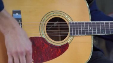 Sokakta oturup gitar çalmaya çalışan genç adam elleri. Hobi konsepti. Adam gitar çalıyor. Parmaklar ve ipler kapansın