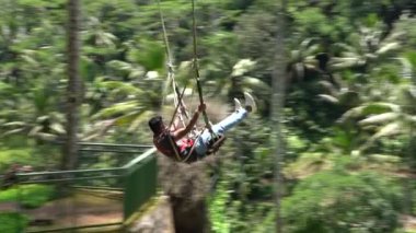 Bali, Indonezya - 11 Mart 2019: Turist ormanda salıncakta sallanıyor. Ubud, Endonezya yakınlarındaki Bali adasının yağmur ormanlarında sallanan insanlar, ağır çekim