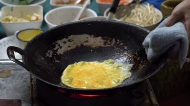 Cook Tayland 'da Bangkok' ta bir gece marketinde Tayland omleti hazırlıyor. Tayland sokak yemeği. Tayland geleneksel mutfağı. Tofu peynirli omlet, yumurta, soya fasulyesi filizi ve sebze, yakın plan.