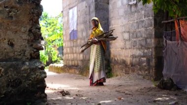 Zanzibar, Tanzanya - 16 Kasım 2019: Kucağı odun dolu Afrikalı kız Doğu Afrika 'da Tanzanya' daki Zanzibar adasında