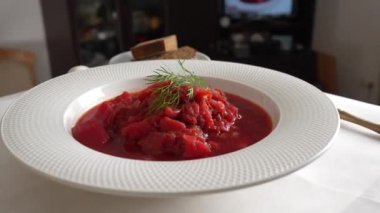 Geleneksel Ukrayna kırmızı çorbası veya kırmızı pancar, patates, havuç, lahana, beyaz kasede fasulye, yakın çekim. Bir tabak kırmızı pancar çorbası çorbası masada döner. Geleneksel Ukrayna yemekleri