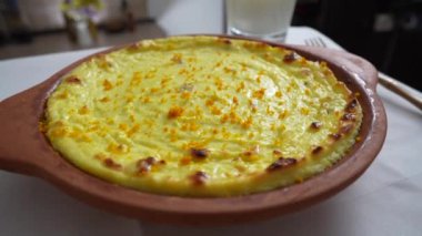 Kuru üzümlü ve irmikli süzme peynir güveci. Fırında pişmiş peynirli güveç ile seramik kase, yakın çekim. Kahvaltı için sağlıklı süt ürünleri.