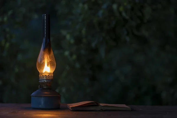 Old Antique Burning Kerosene Lamp Open Book Wooden Table Close — Stockfoto