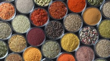 Arka planda yemek pişirmek için çeşitli aromatik baharatlar, tohumlar ve kuru otlar. Smal cam kaselerde dönüyorlar, kapatıyorlar, üstten bakıyorlar.
