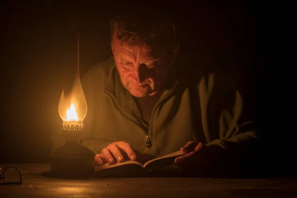 Man Reads Book Light Kerosene Lamp Night Time Close Royaltyfria Stockfoton