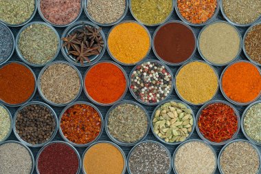 Arka planda yemek pişirmek için aromatik baharatlar, tohumlar ve kuru otlar küçük cam kaselerde, yakın plan, üst görüş
