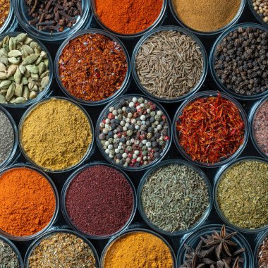 Arka planda yemek pişirmek için aromatik baharatlar, tohumlar ve kuru otlar küçük cam kaselerde, yakın plan, üst görüş