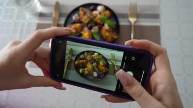 Kız, akıllı telefon kullanarak ızgara şeftali salatasının mozzarella ile fotoğrafını çekiyor. Kadın eli, modern akıllı telefonla yiyeceklerin fotoğrafını çeker. Yaklaş, 4K