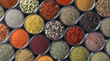 Arka planda yemek pişirmek için çeşitli aromatik baharatlar, tohumlar ve kuru otlar. Smal cam kaselerde dönüyorlar, kapatıyorlar, üstten bakıyorlar.