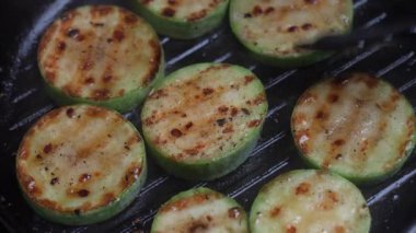 Baharatlı ızgara organik yeşil kabak, sağlıklı vejetaryen yemekleri, yakın plan. Izgaradaki kabağı maşayla, vejetaryen yemeğiyle çevir.