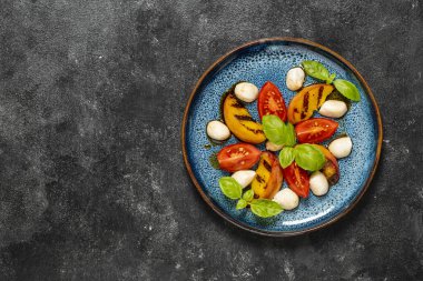 Izgara şeftali salatası, mozzarella, yeşil fesleğen ve sos. Siyah arkaplanda taze gurme salatası, kapat, üst görünüm, kopyala