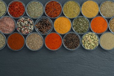 Arka planda yemek pişirmek için aromatik baharatlar, tohumlar ve kuru otlar küçük cam kaselerde, üst görünümü kapat, boşluğu kopyala
