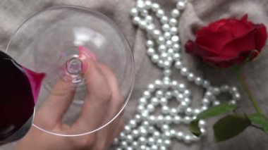 Genç beyaz bir kadın, zeytinli bir martini ile arka planda inci bir kolye ve kırmızı bir gül tutuyor. Yakın plan, üst manzara.