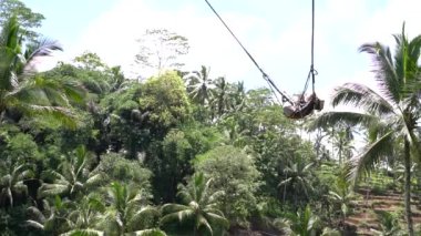 Bali, Indonezya - 11 Mart 2019: Turist ormanda salıncakta sallanıyor. Ubud, Endonezya yakınlarındaki Bali adasının yağmur ormanlarında sallanan insanlar, ağır çekim