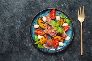 Peynirli ızgara şeftali salatası, jambon, kırmızı domates, yeşil fesleğen ve soya sosu. Siyah arkaplanda taze gurme salatası, kapat, üst görünüm, kopyala