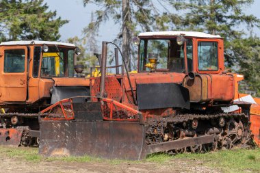 Old bulldozer on a sunny day with a bucket to move the earth in an abandoned factory, close up . Ukraine, Europe