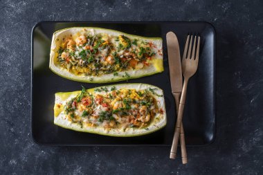Zucchini stuffed with shrimps, vegetables and cheese. Baked zucchini boats, top view, close up