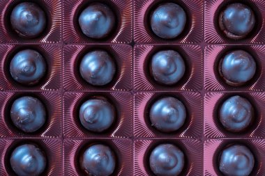 Close up brown chocolate candy background. Assortment of chocolate candies sweets in the box, top view