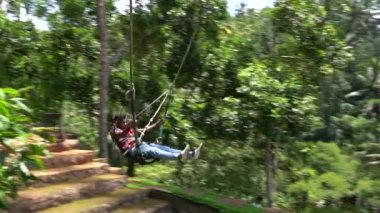 Bali, Indonezya - 11 Mart 2019: Turist ormanda salıncakta sallanıyor. Ubud, Endonezya yakınlarındaki Bali adasının yağmur ormanlarında sallanan insanlar, ağır çekim