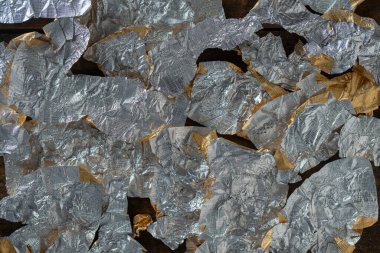 Candy wrappers made of foil with the reverse side for background, close up, top view. Many lot of crumpled wrapping from under chocolates