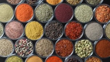 Arka planda yemek pişirmek için çeşitli aromatik baharatlar, tohumlar ve kuru otlar. Smal cam kaselerde dönüyorlar, kapatıyorlar, üstten bakıyorlar.