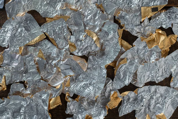 Candy wrappers made of foil with the reverse side for background, close up, top view. Many lot of crumpled wrapping from under chocolates