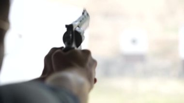 Adam atış poligonundaki hedeflere tabancayla ateş ediyor. Yaklaş, bulanık odaklan. Atış talimi yaparken arkadan ateş eden bir adamın görüntüsü. Yavaş çekim