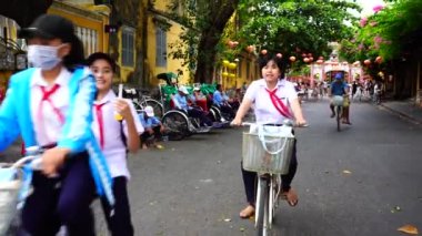 Hoi An, Vietnam - 29 Haziran 2020: Vietnamlı genç kızlar eski Hoi An, Vietnam 'ın nehir kenarında bisiklet sürüyorlar.