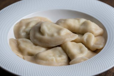 Beyaz tabakta süzme peynirle doldurulmuş lezzetli hamur köfteleri, yakından. Ukrayna mutfağı