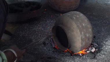 Bir demirci Udaipur, Rajasthan, Hindistan 'daki geleneksel bir atölyede açık ateşte tencere yapar.