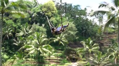 Bali, Indonezya - 11 Mart 2019: Turist ormanda salıncakta sallanıyor. Ubud, Endonezya yakınlarındaki Bali adasının yağmur ormanlarında sallanan insanlar, ağır çekim