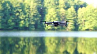 Kiev, Ukrayna - 01 Ekim 2021: DJI Maviç Air 2S İHA 'sı, bir önceki Maviç modeline göre büyük bir güncelleme yaparak, arka planda asılı duruyor. DJI Mavic Air 2S İHA 'sı orman gölünde uçuyor.