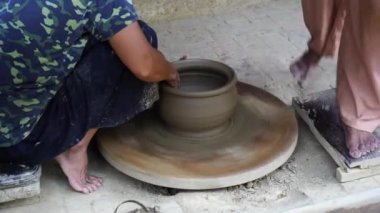Bir kadın çömlekçinin yakın plan çekimi ayağıyla bir tekerleği döndürür ve eski şehir Hoi An, Vietnam 'da çömlek imalatında elleriyle güzel bir çömlek yapar.